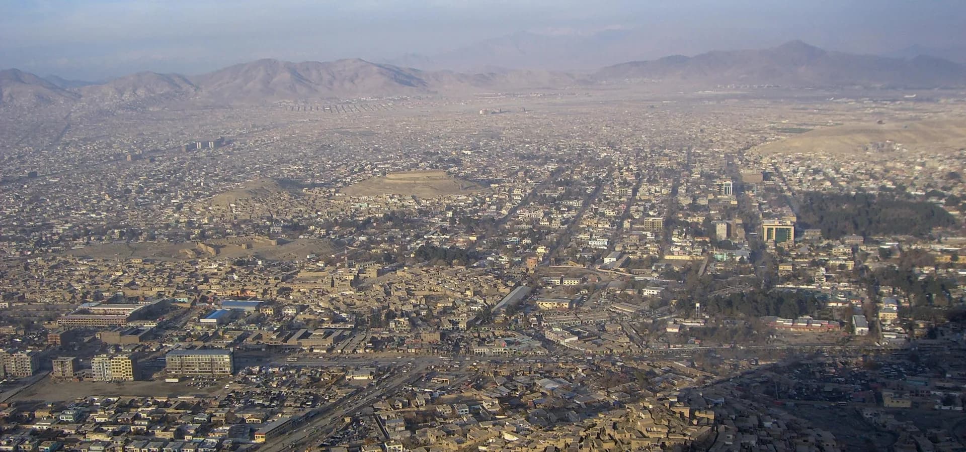 View from TV Hill over Kabul, low buildings filling the valley toward a ridge of bare mountains