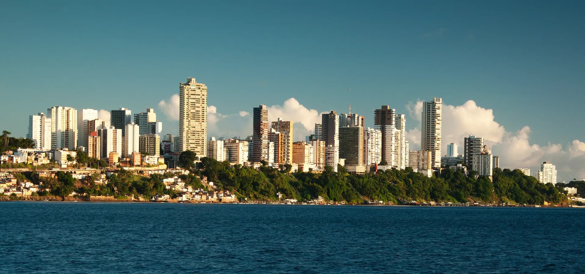 Torres de apartamentos de Salvador sobre una ladera verde, vistas a través de las aguas azules y tranquilas de la Bahía de Todos los Santos