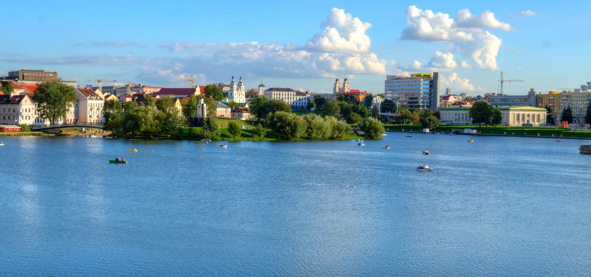Die breite Switsloch im Sommer, mit der Troizkaja Pridmestje und den Kirchtürmen der Oberstadt am anderen Ufer unter weißen Wolken