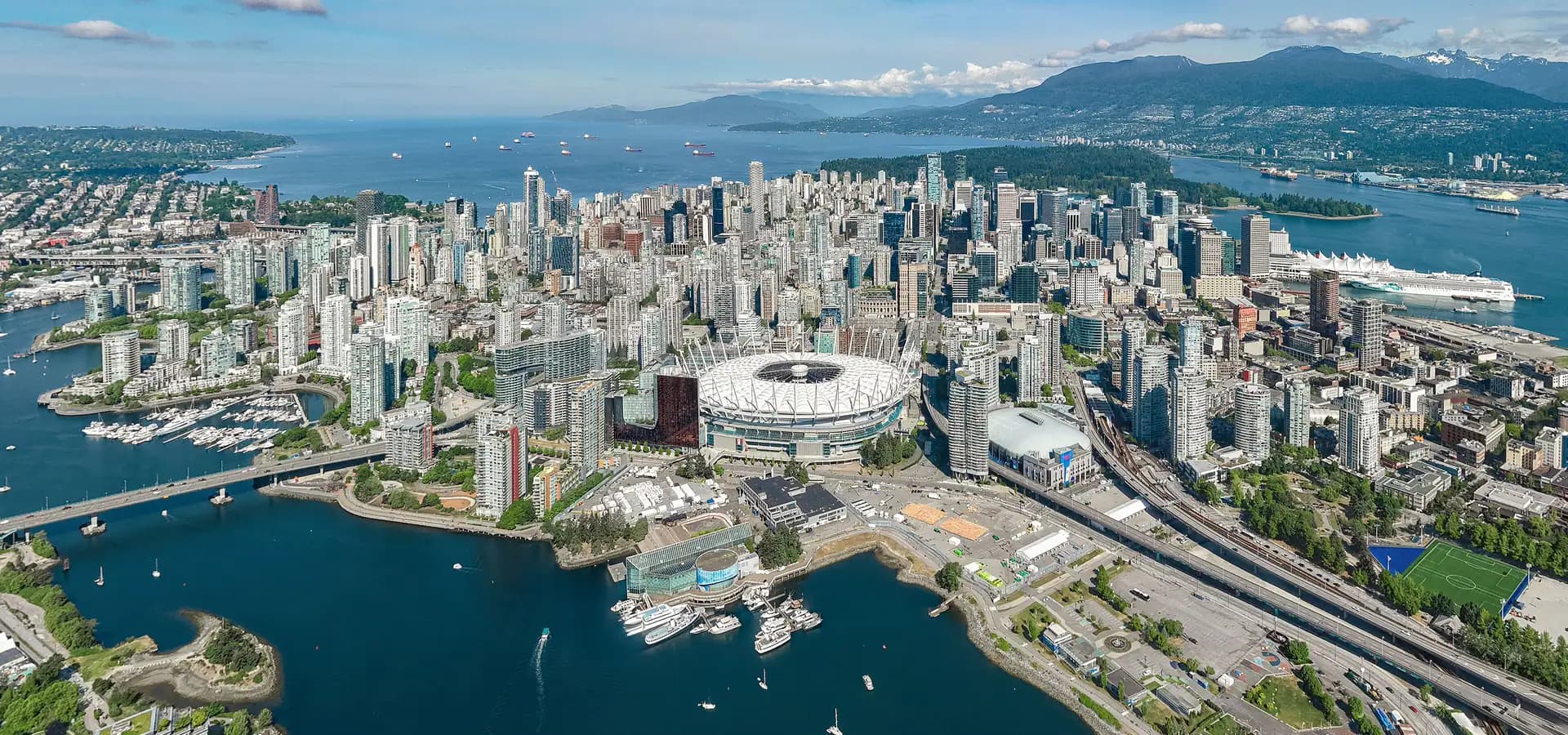 Vista aérea de las torres del centro de Vancouver entre False Creek y el puerto, con montañas al fondo