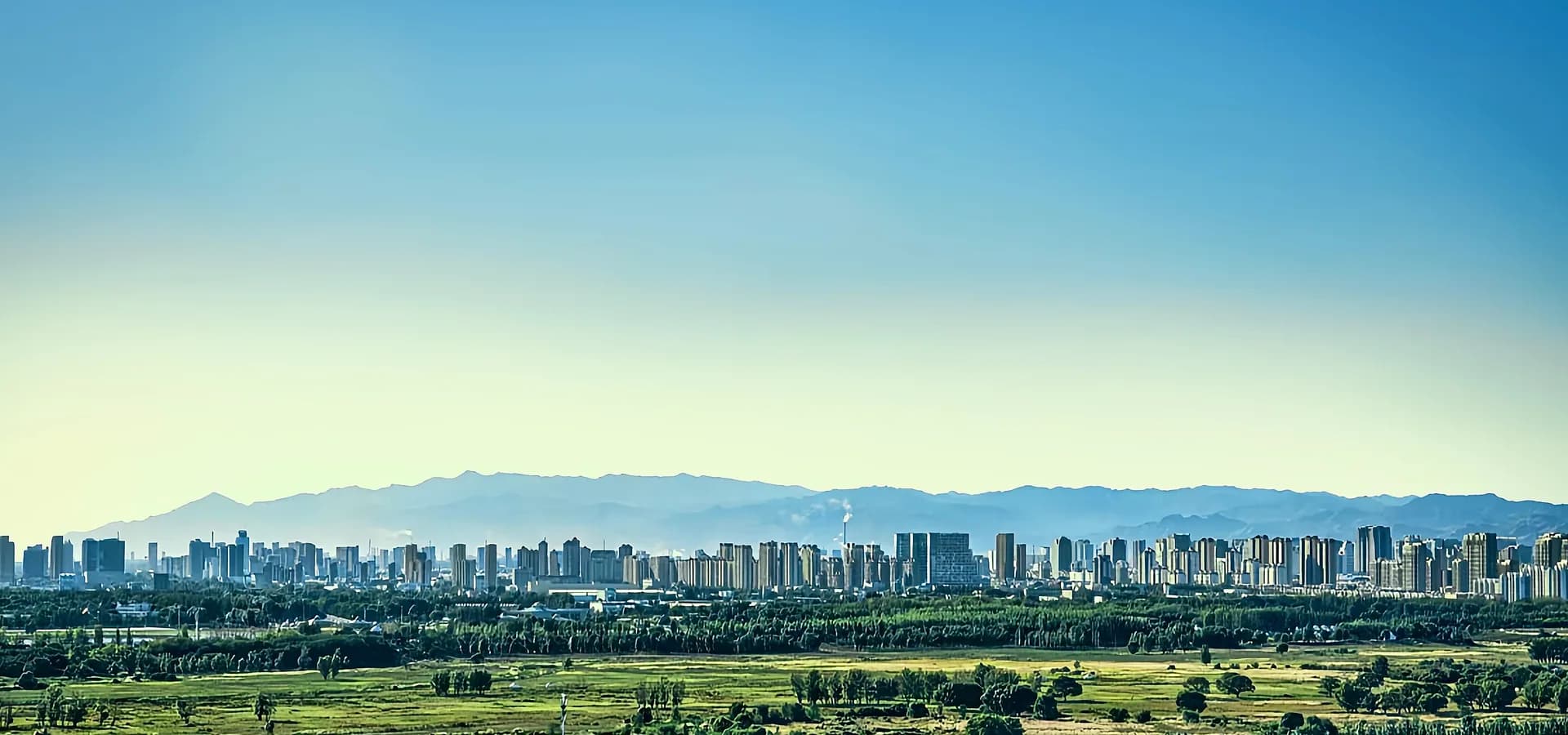 El horizonte de Baotou extendido a lo largo de los montes Yin, con la verde pradera de Saihantala al frente