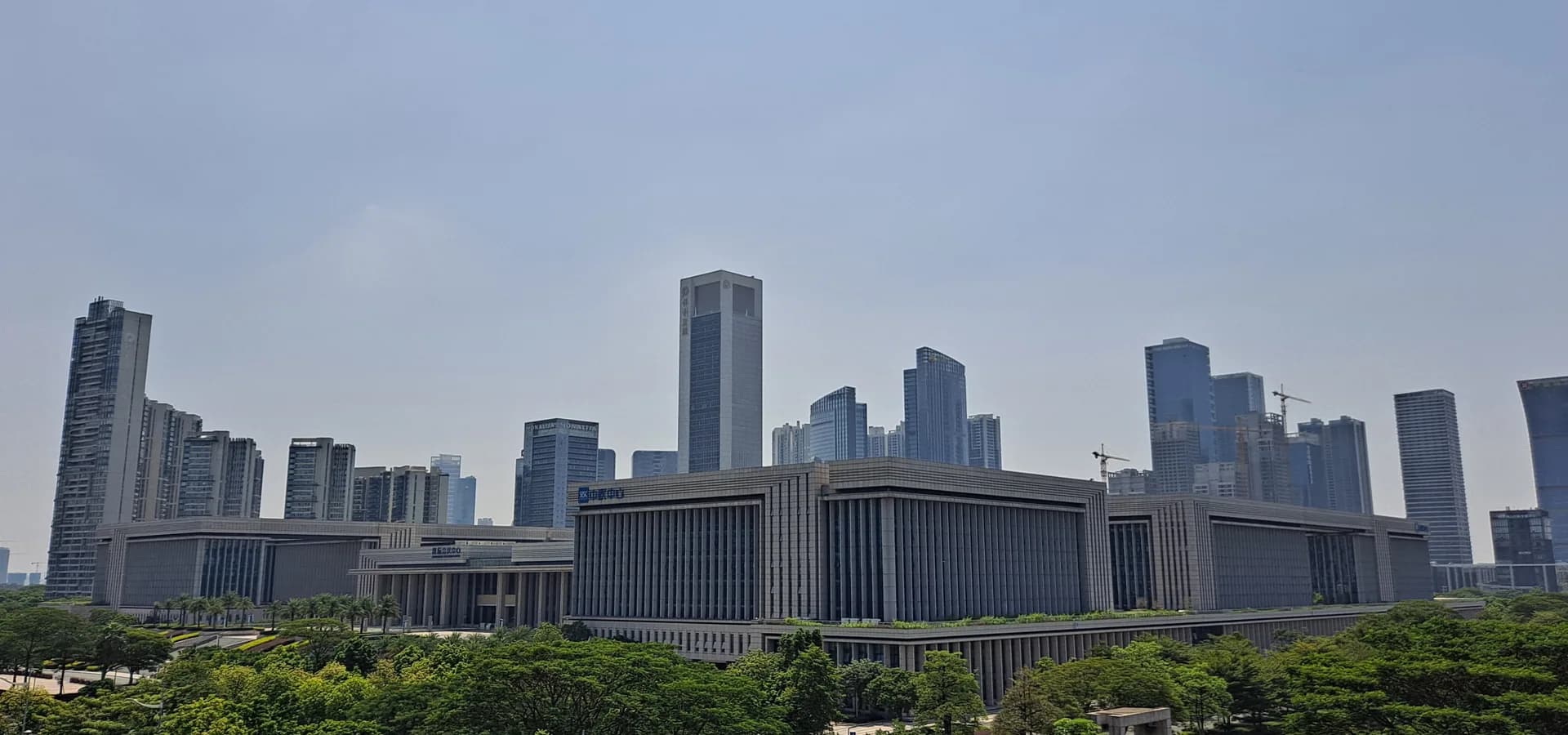 Hochhäuser der Neustadt Dongping in Foshan ragen hinter langen Bürgerhallen und grünen Parkanlagen auf
