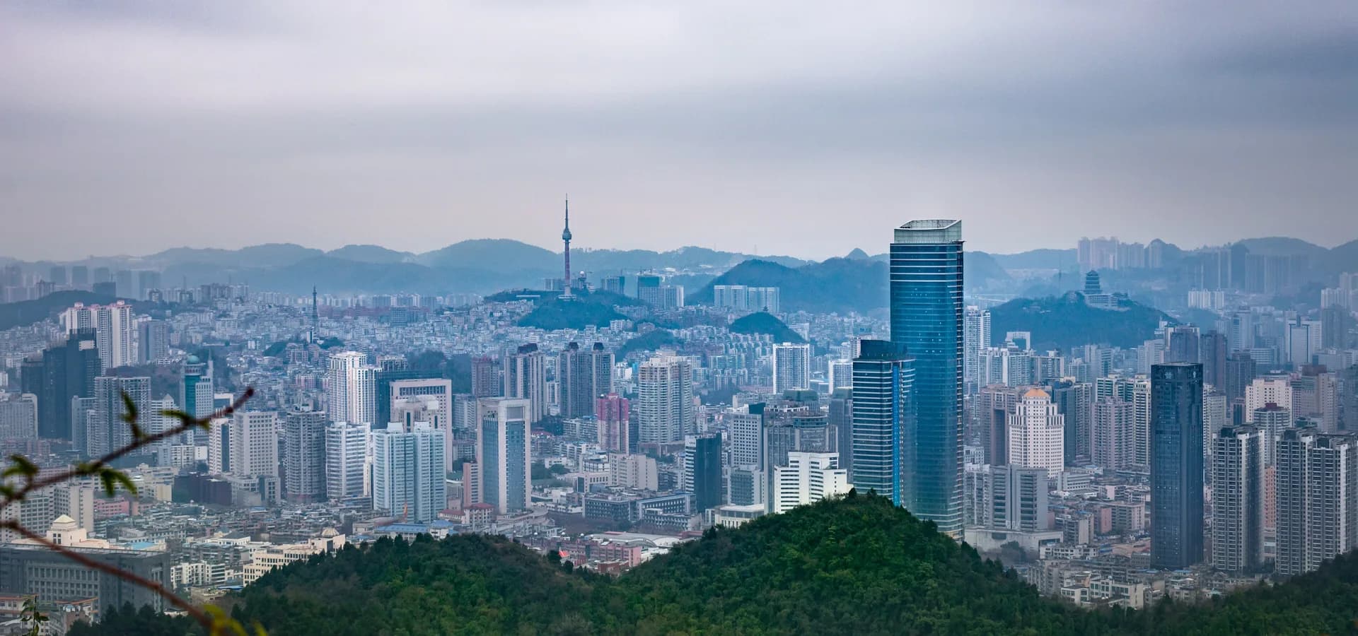 Los edificios de Guiyang se alzan entre colinas verdes y arboladas, con montañas brumosas en el horizonte