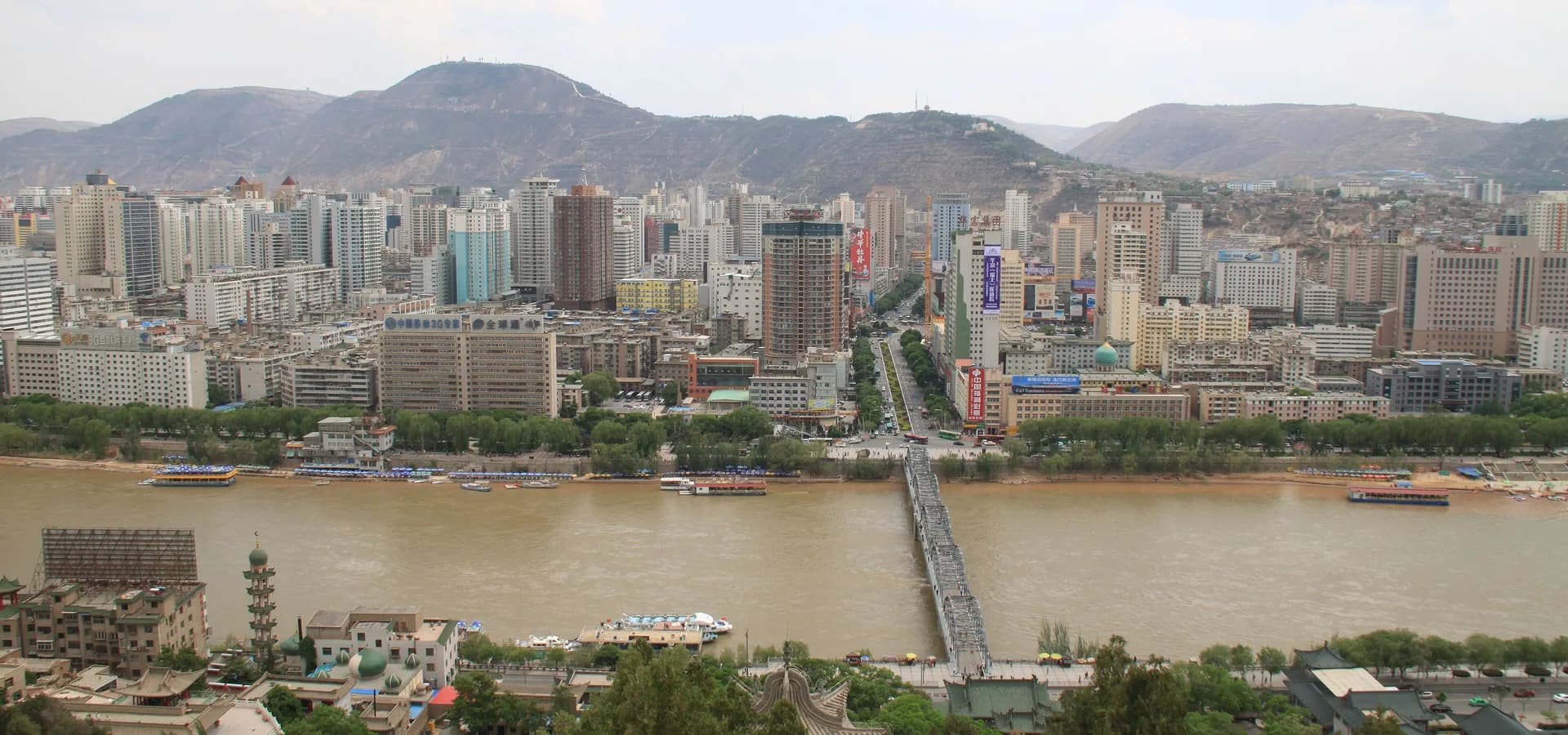 Lanzhou vista da Montanha do Pagode Branco, com o Rio Amarelo e a Ponte Zhongshan embaixo e colinas secas mais além