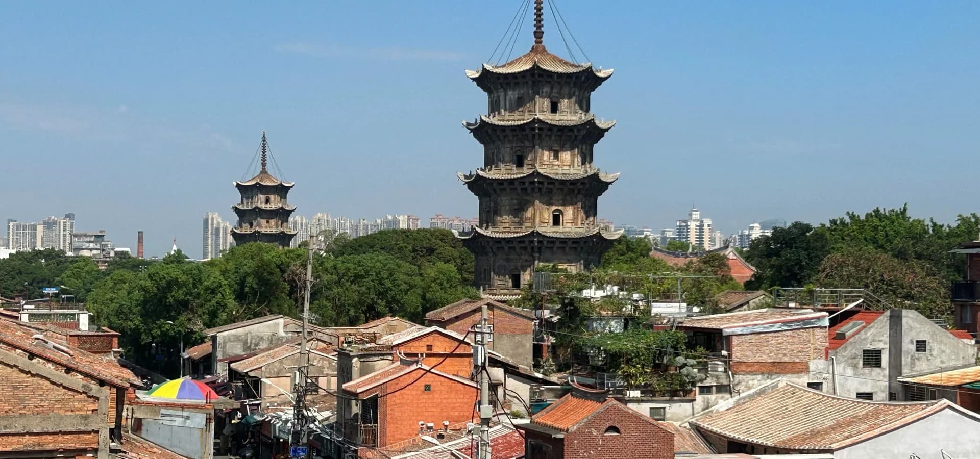 Die zwei Steinpagoden des Kaiyuan-Tempels ragen über rote Ziegelhäuser und Ziegeldächer an der West Street in Quanzhou