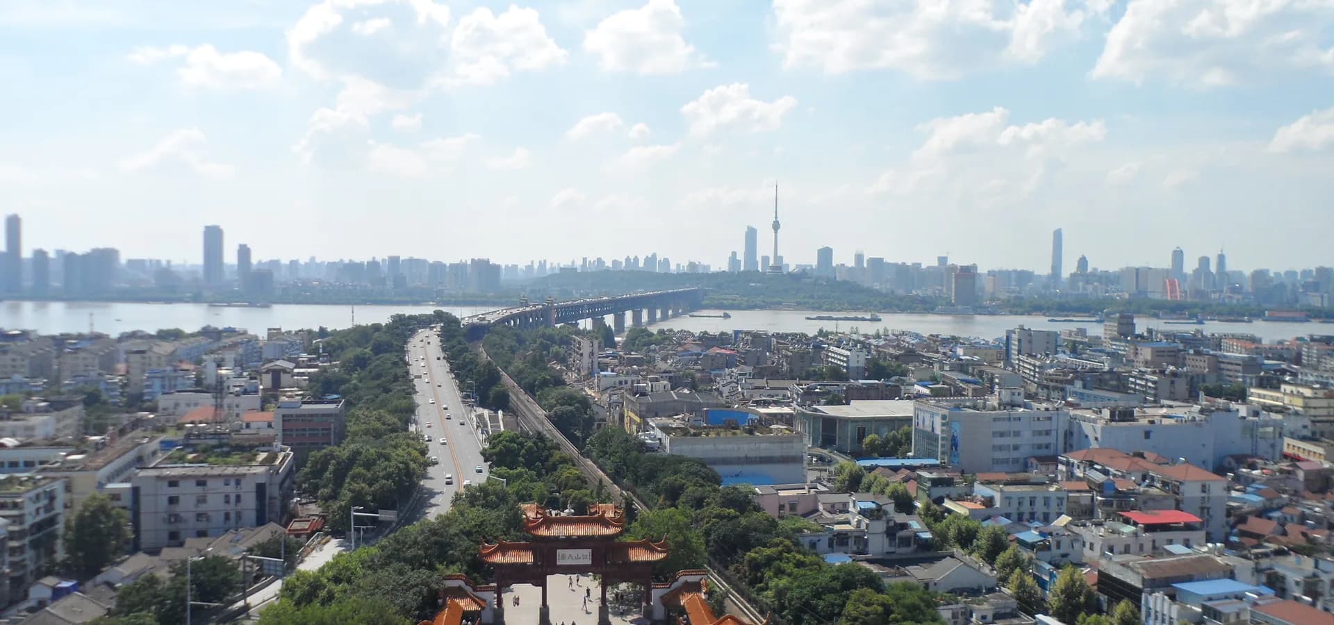 Wuhan vista desde la Torre de la Grulla Amarilla, con el puente del río Yangtsé cruzando hacia el horizonte urbano bajo un cielo azul