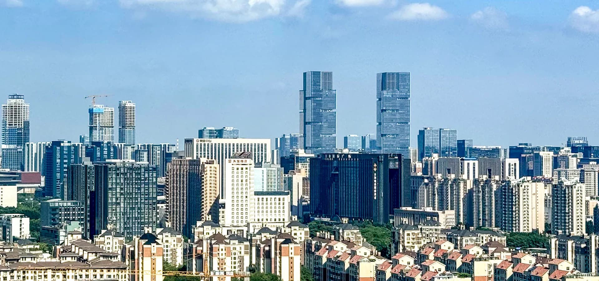 Amplo panorama diurno da Nova Área de Zhengdong, com torres de vidro acima de fileiras de prédios de apartamentos em Zhengzhou.