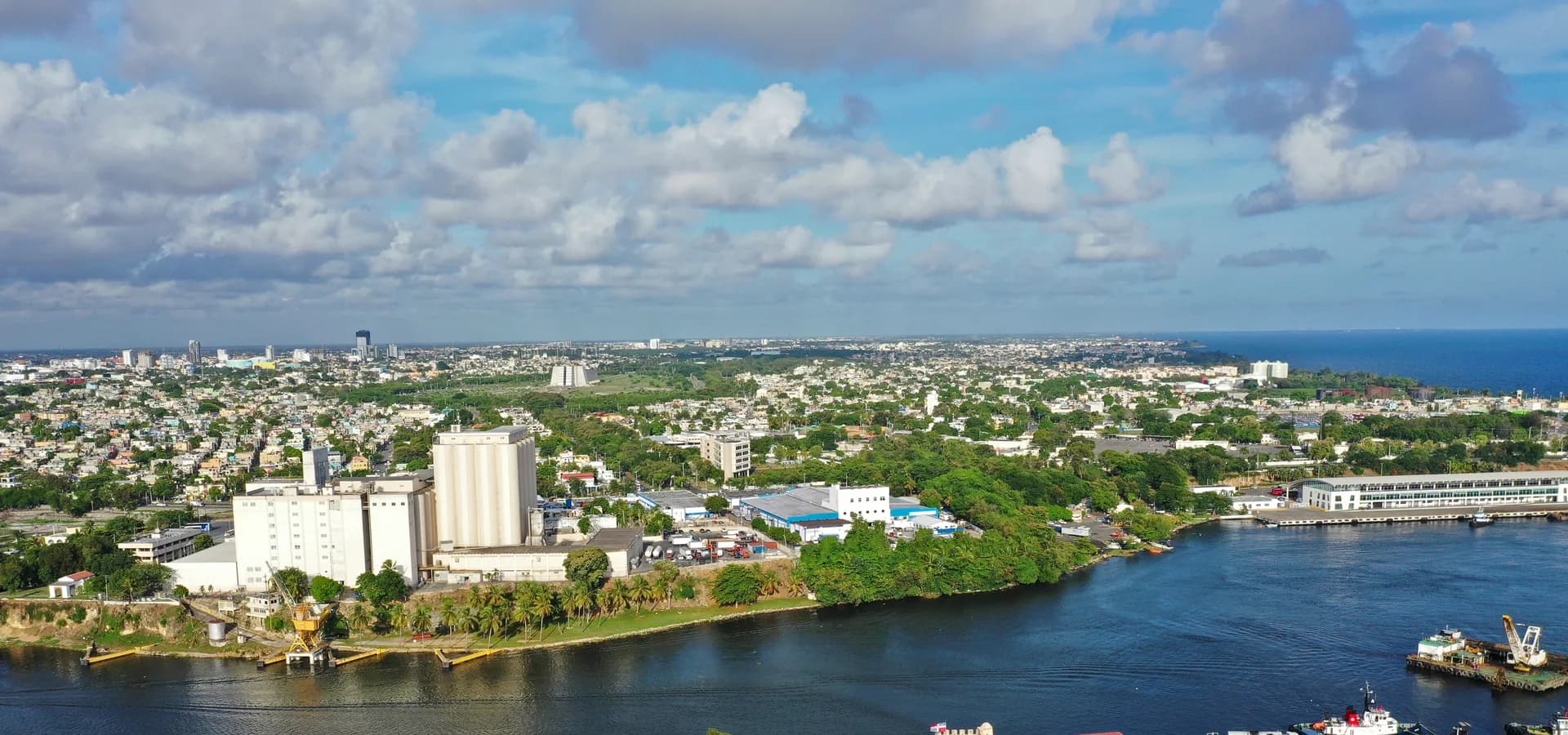 Vista aérea del río Ozama hacia la extensión baja y verde de Santo Domingo Este y el mar Caribe
