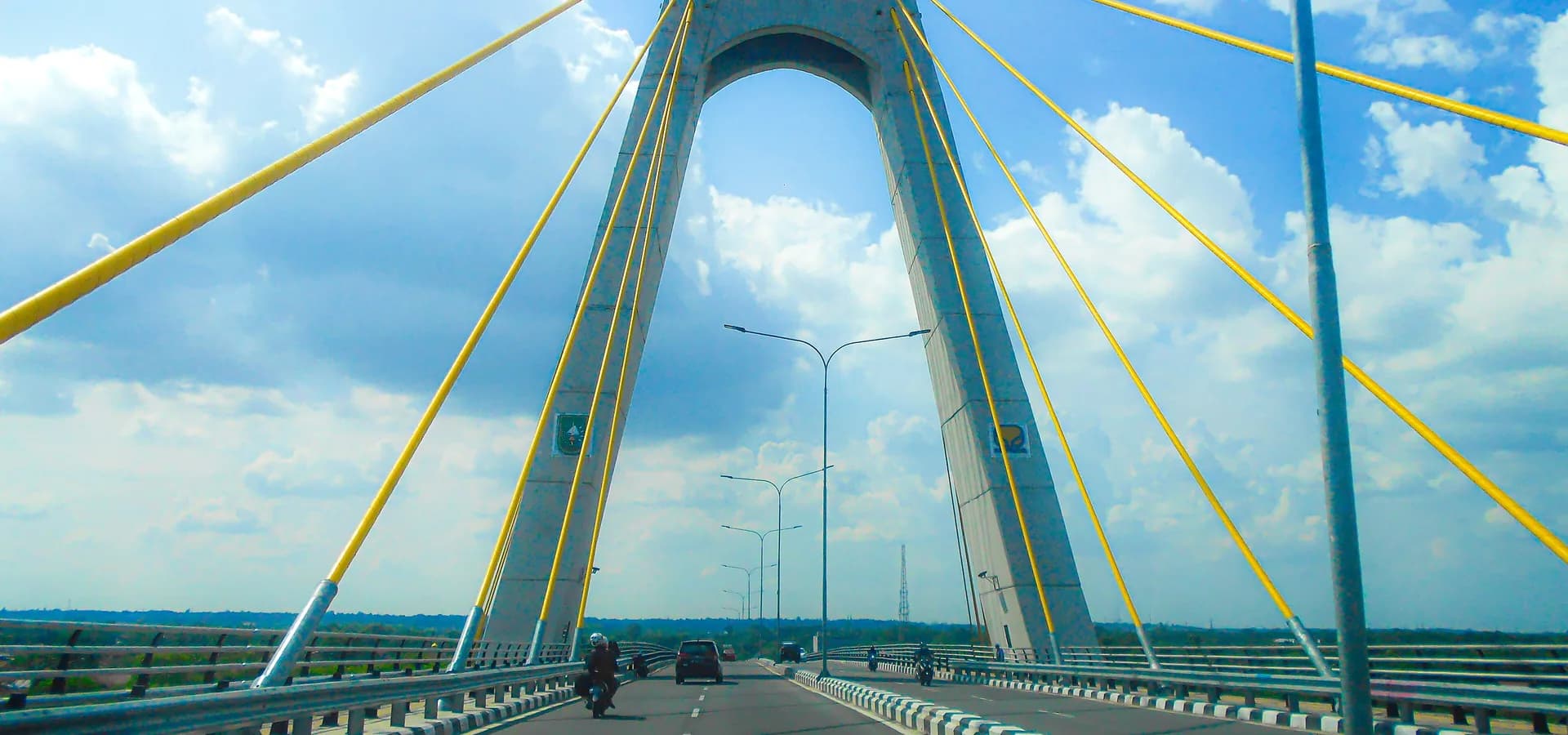 Road over the Siak IV bridge in Pekanbaru, its concrete pylon and yellow cables against a blue sky
