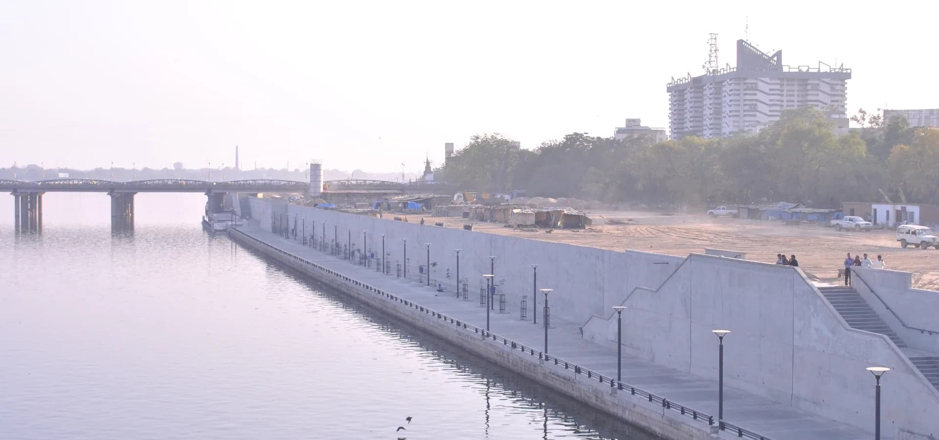 Rio Sabarmati parado com a longa orla, uma ponte e prédios da cidade sob a suave luz da manhã