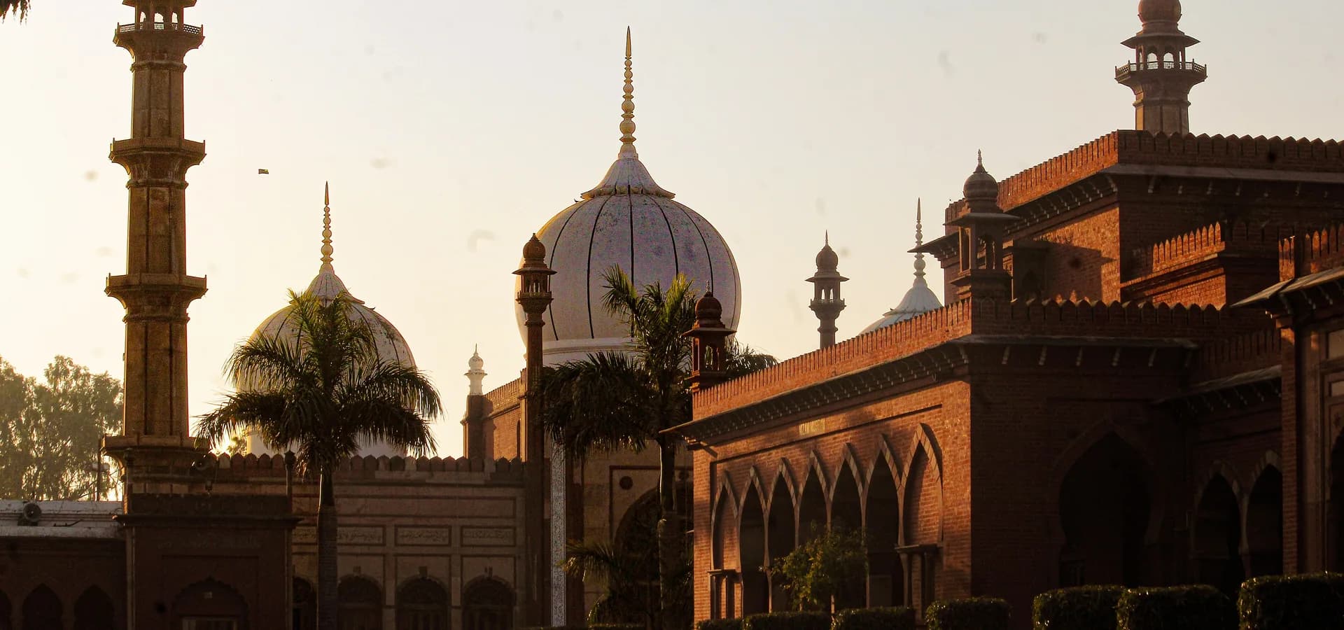 Cúpulas blancas y un alto minarete de la Jama Masjid de la Universidad Musulmana de Aligarh brillan en la hora dorada junto a pabellones de ladrillo rojo
