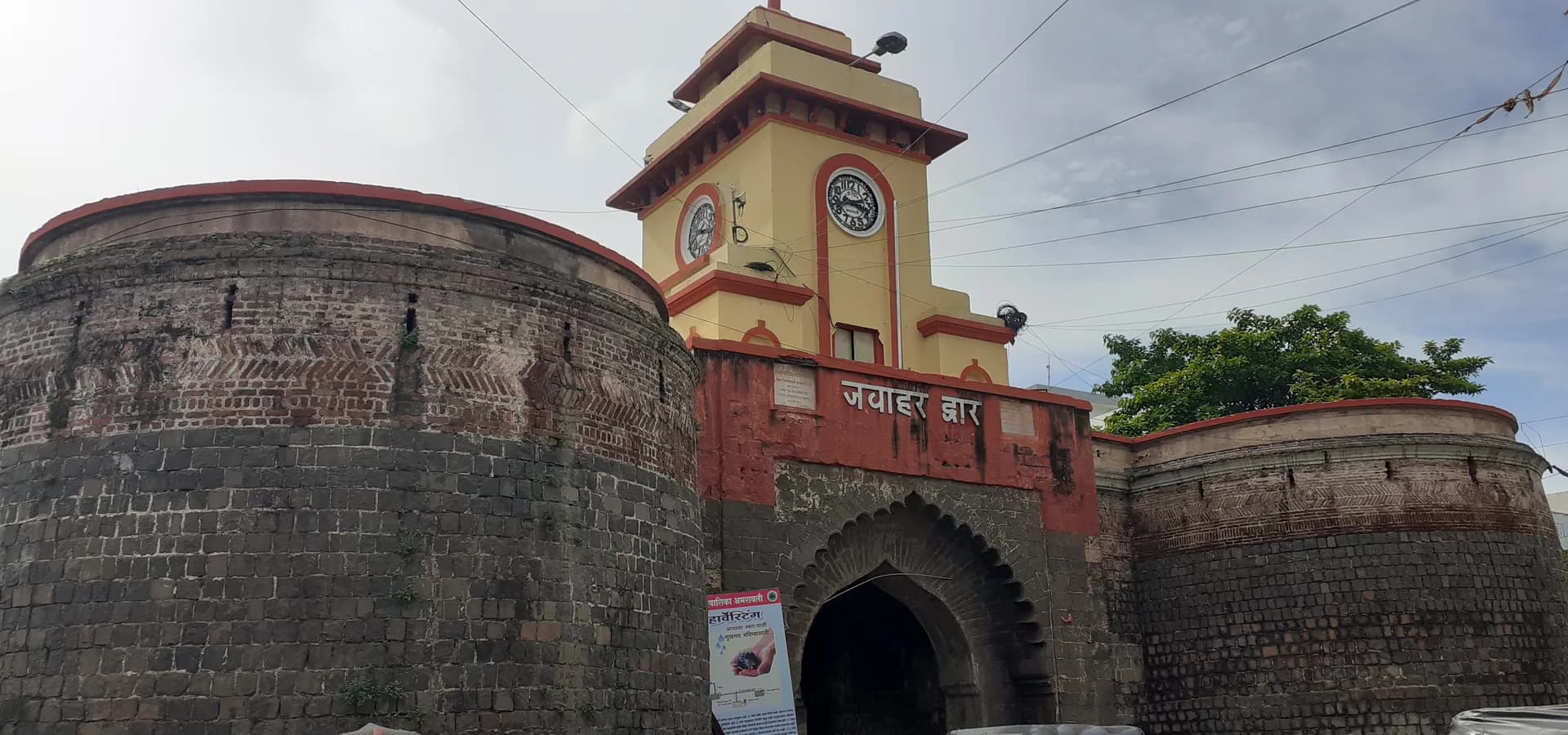 Puerta Jawahar en Amravati, una torre de reloj amarilla sobre un portal con arco entre bastiones redondos de piedra