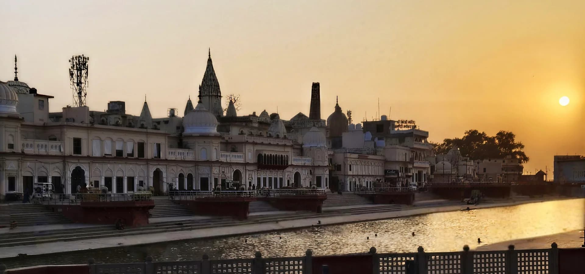 Agujas y cúpulas de templos a lo largo de los ghats de Ram ki Paidi mientras el sol se pone sobre el agua en Ayodhya