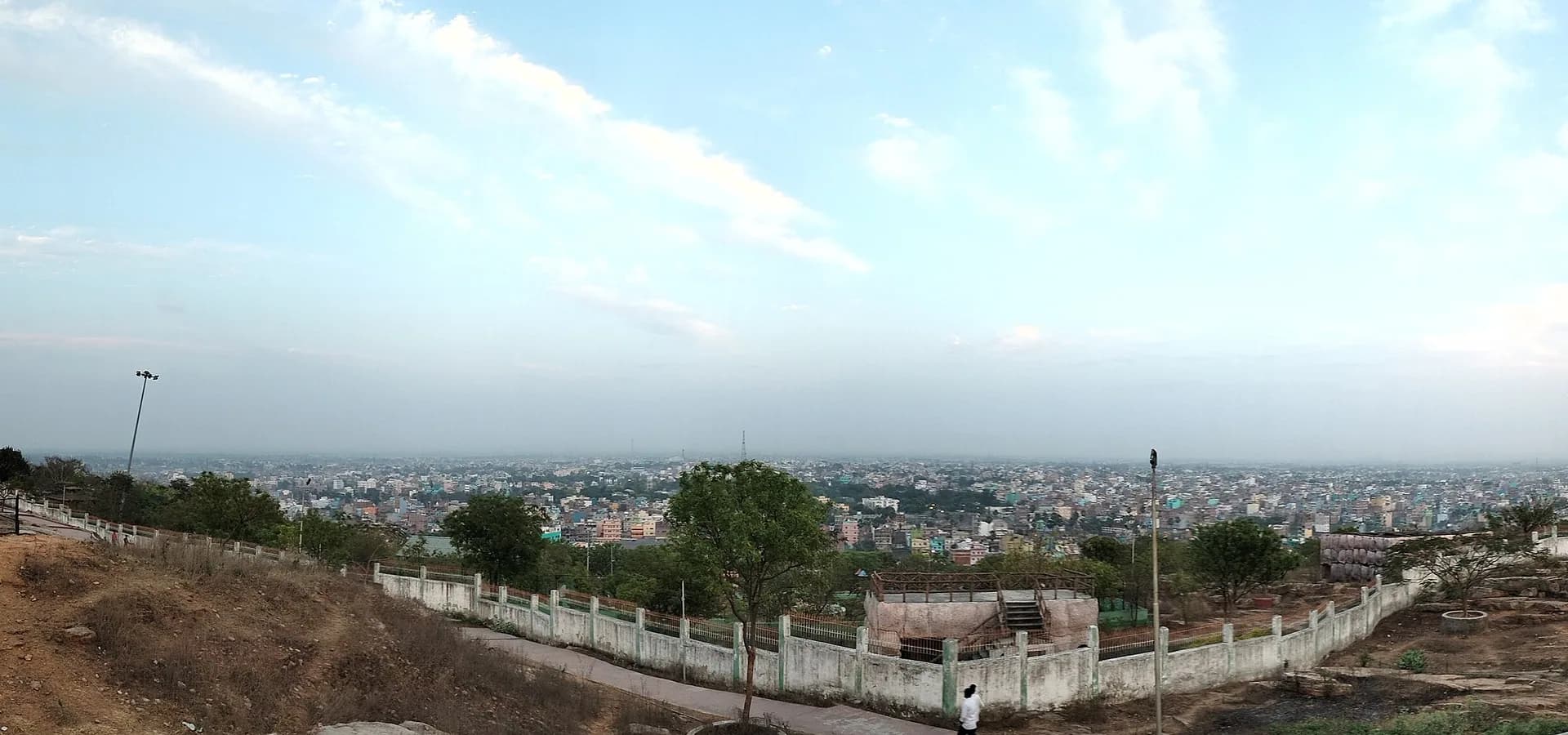 Wide view from Badi Pahadi hilltop park over the flat rooftops of Bihar Sharif under a pale blue sky