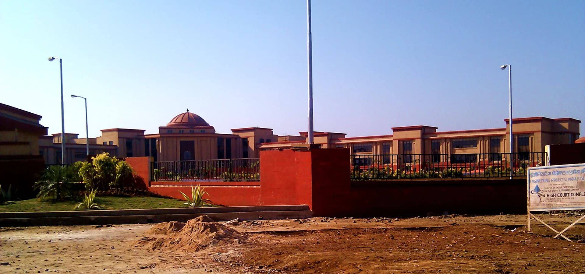 The long sandstone-colored Chhattisgarh High Court building with a red dome under a clear blue sky near Bilaspur