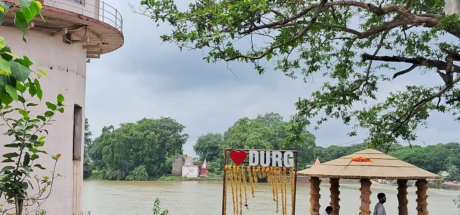 Riverside promenade in Durg with an I Love Durg sign, a small gazebo and trees across the wide river