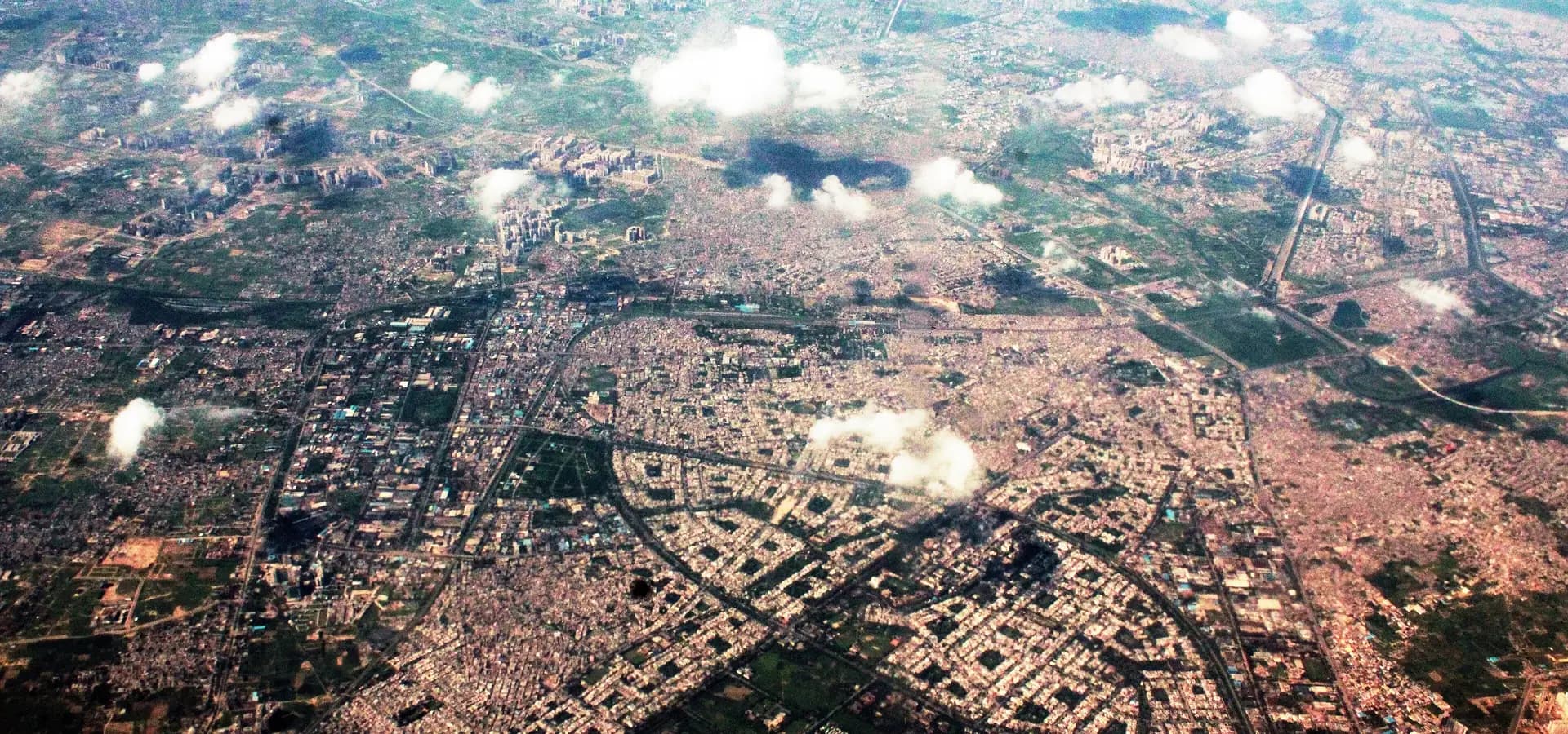 Vista aérea de Ghaziabad com as ruas curvas de Raj Nagar, manchas verdes e nuvens baixas sobre a planície