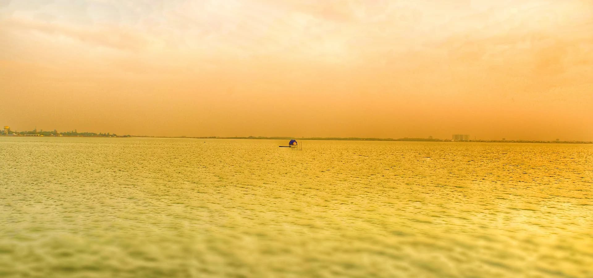 O lago Ramgarh Tal, em Gorakhpur, brilhando dourado sob um céu enevoado, com uma fina linha da cidade na margem distante