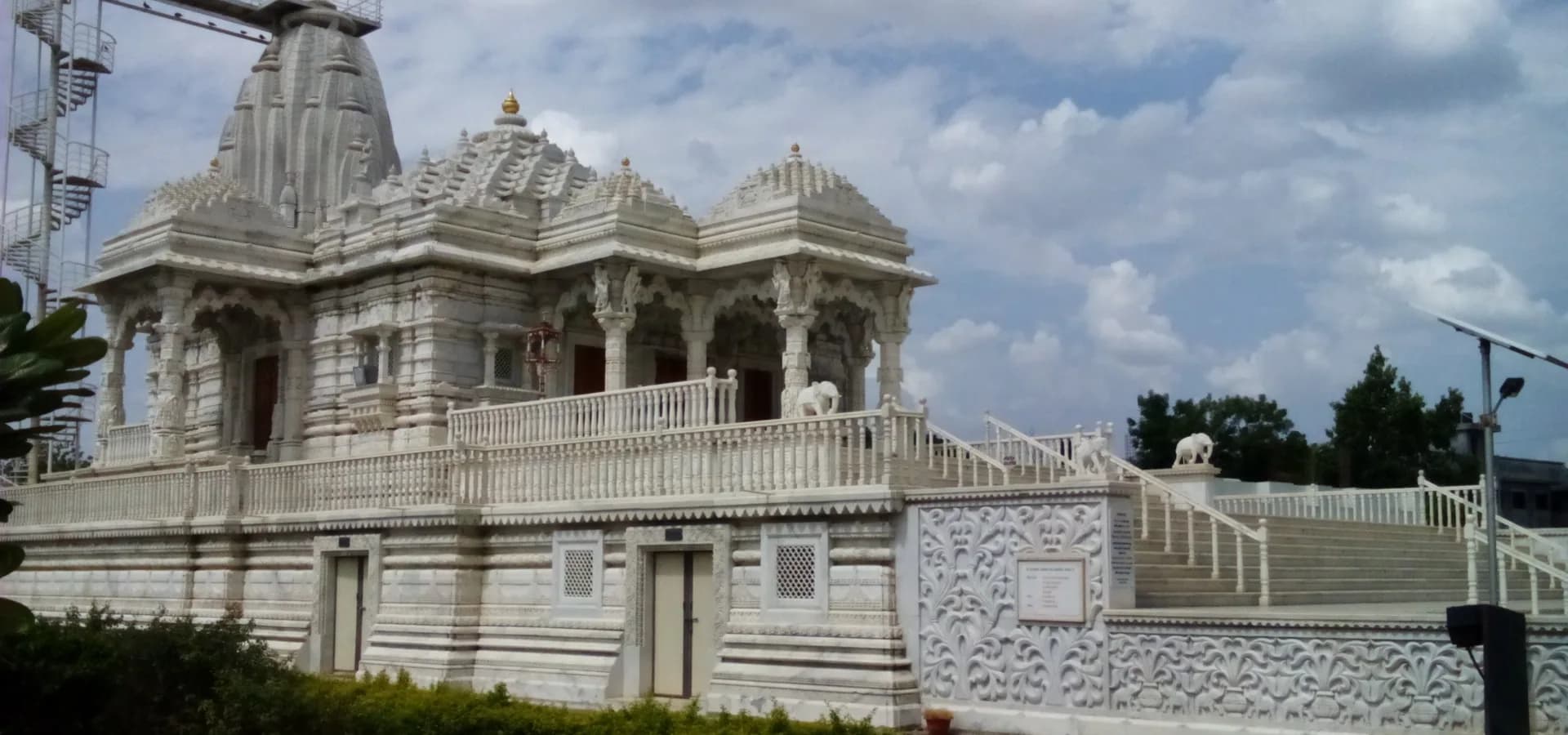 Templo jainista de mármore branco entalhado em Dadawadi, Jalgaon, com elefantes de pedra e um amplo céu nublado