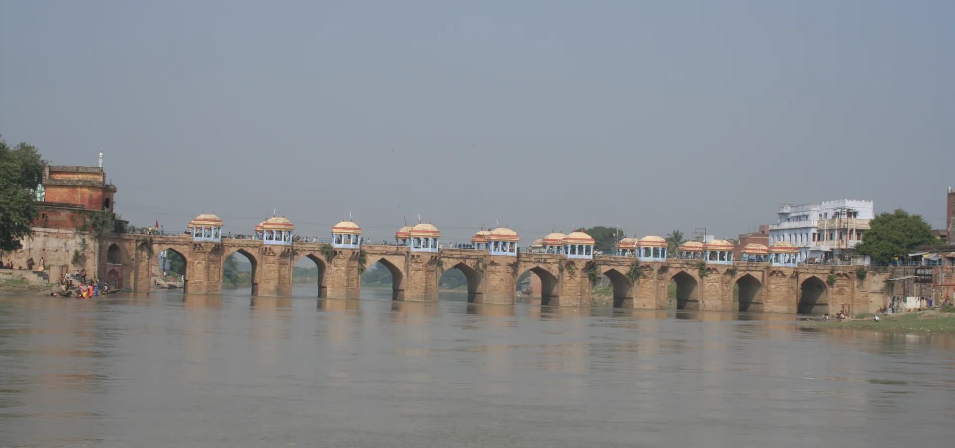 The arched Shahi Bridge with a row of small domed kiosks stretching across the wide Gomti River in Jaunpur