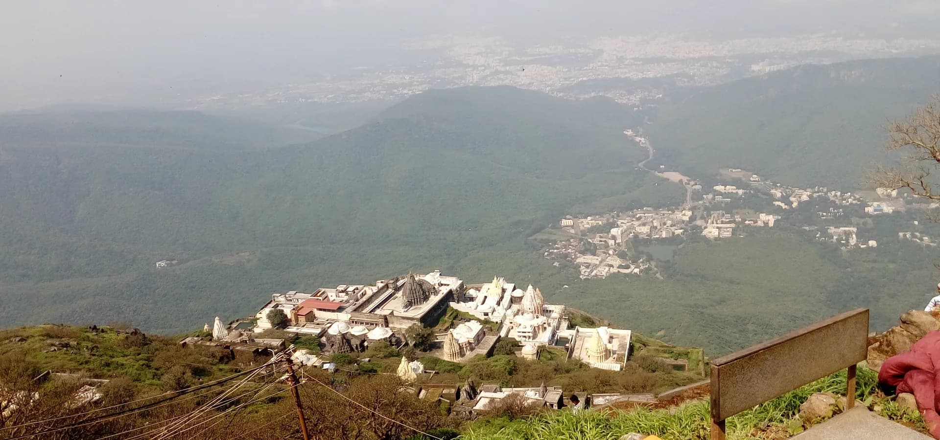 जंगली पहाड़ियों के ऊपर गिरनार की चोटी पर सफ़ेद जैन मंदिर, दूर मैदान में फैला जूनागढ़ शहर