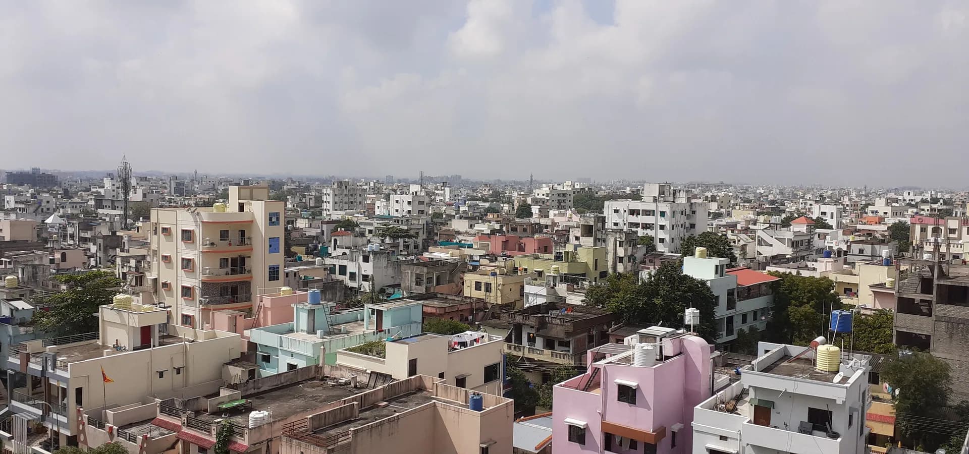 Bloques de apartamentos pastel y tanques de agua en azoteas del sur de Nagpur que se extienden hasta el horizonte bajo nubes suaves
