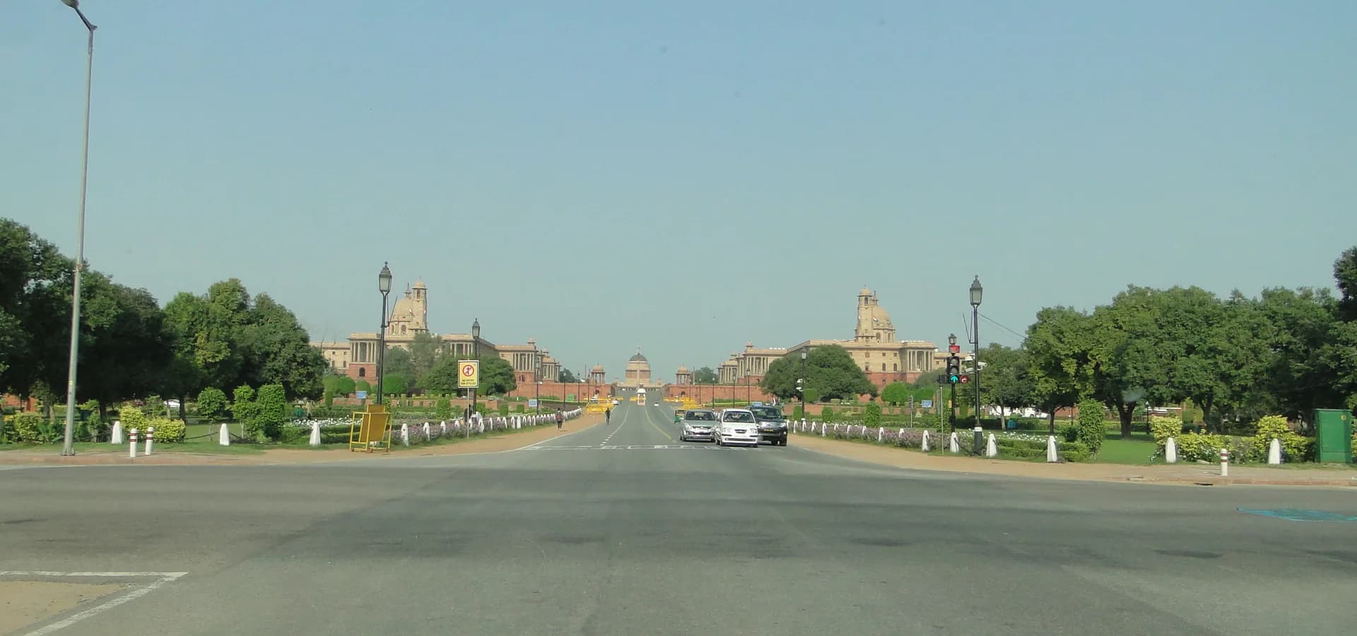 Wide Kartavya Path avenue lined with lawns and trees, leading to the domed Secretariat buildings on Raisina Hill