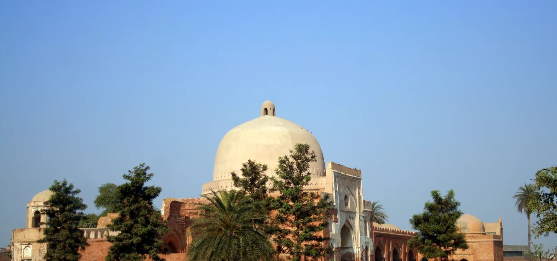 Die helle Kuppel und das Torbogen-Portal von Baburs Kabuli-Bagh-Moschee in Panipat unter klarem blauem Himmel