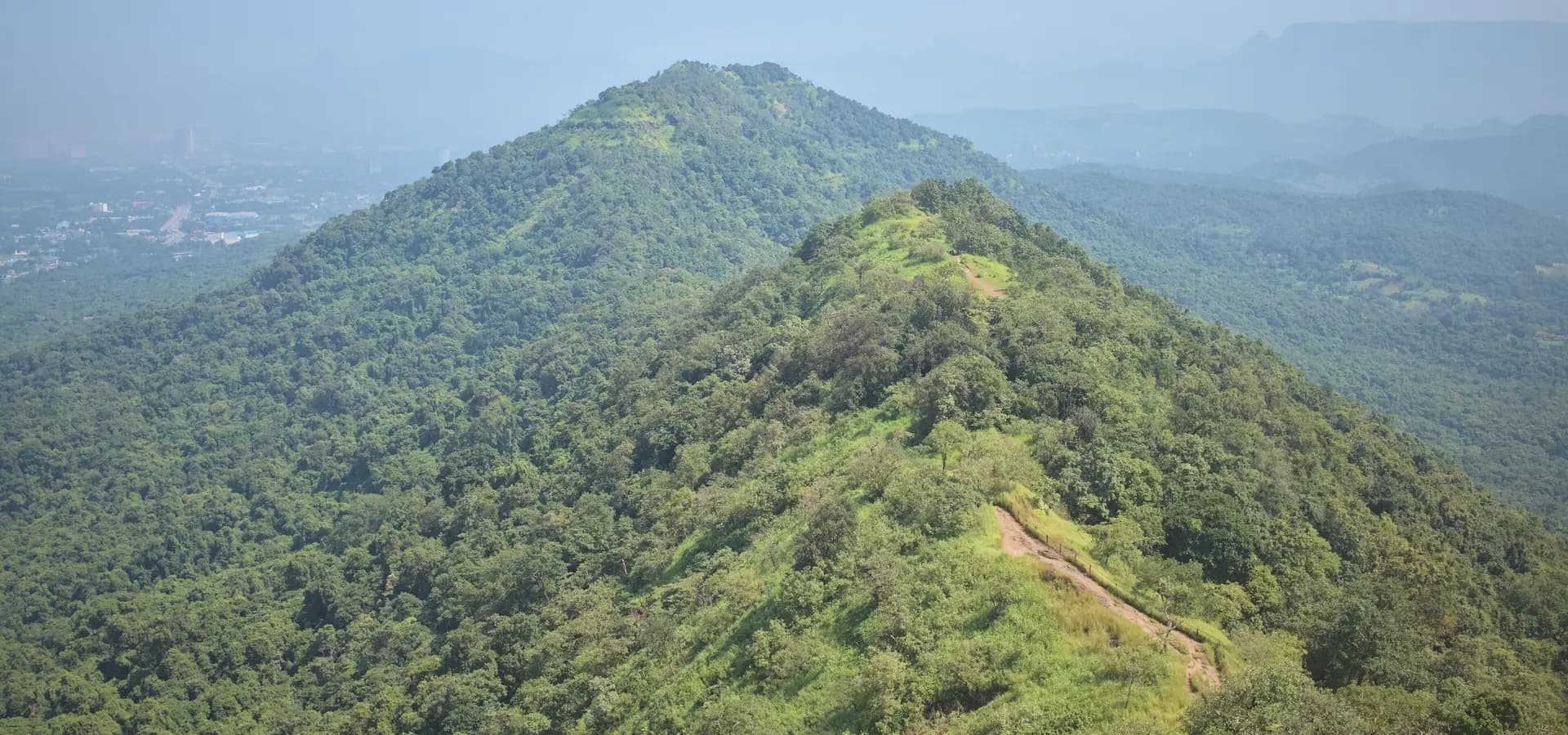 Verdes cordilleras boscosas vistas desde el fuerte de Karnala, con la zona de Panvel y colinas lejanas que se desdibujan en la bruma azul