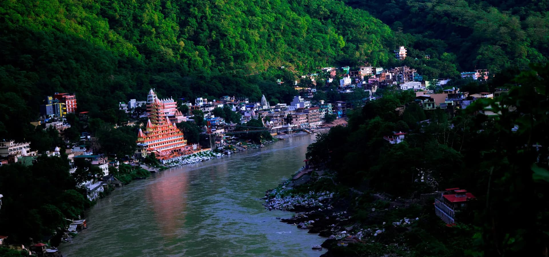 El Ganges serpenteando por un valle verde junto al templo escalonado Tera Manzil y casas en la ladera