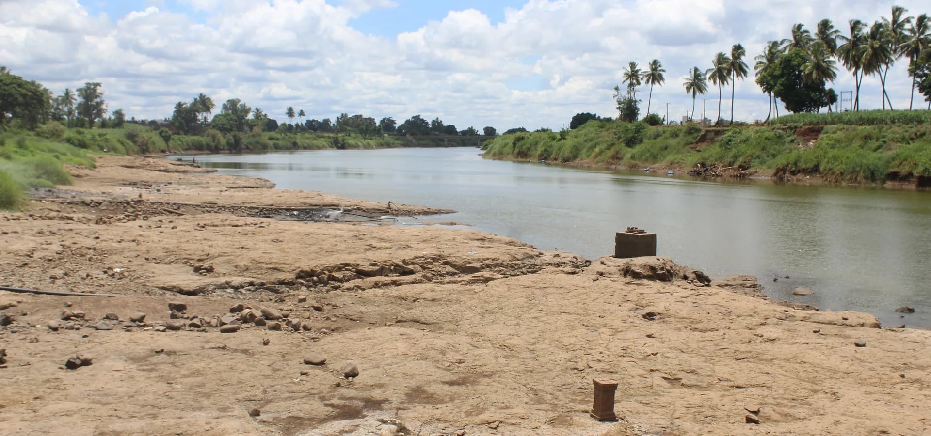 Der Krishna-Fluss schwingt sich unter weißen Monsunwolken an grünen, palmengesäumten Ufern bei Sangli vorbei