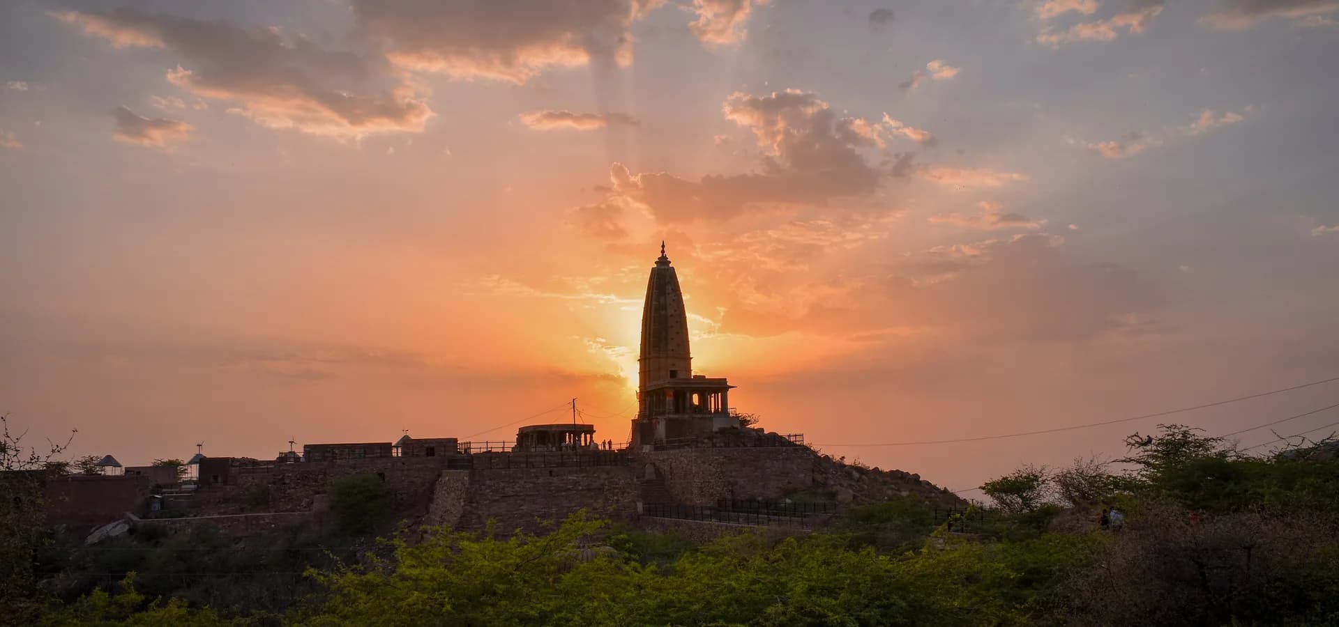 El templo de Harshnath en la colina Harsh, en silueta contra un cielo naranja de atardecer cerca de Sikar