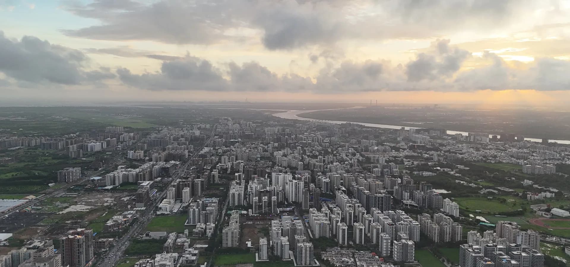 Vista aérea de las torres de Vesu en Surat bajo un cielo nublado al atardecer, con el río Tapi curvándose hacia el mar