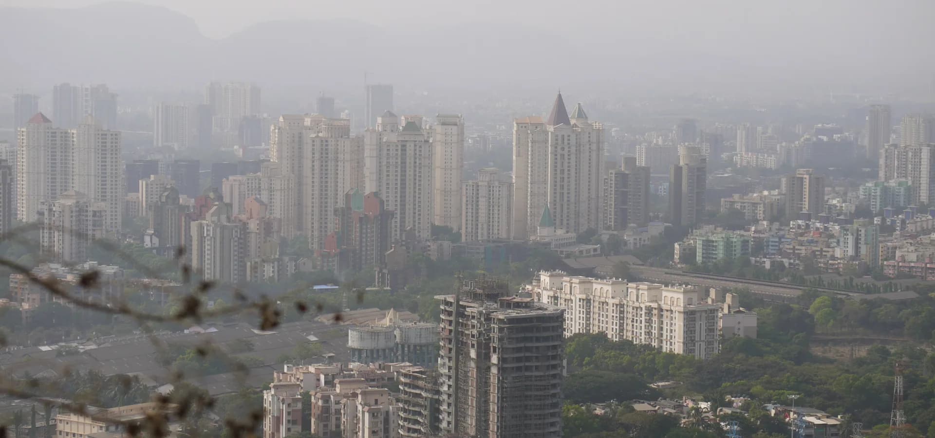 Hazy view over Thane towers and green slopes from the Yeoor Hills, with hills on the horizon