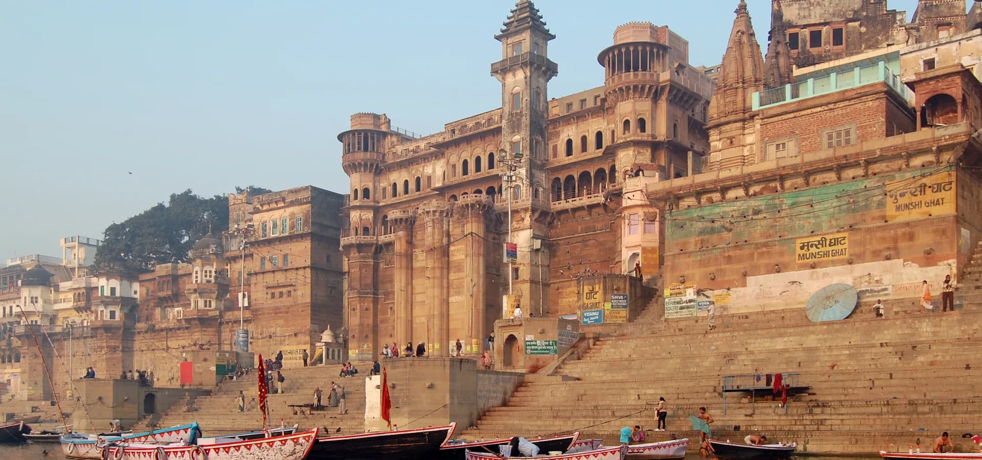 Sandsteinpaläste und Steinstufen des Munshi Ghat steigen unter blassem Morgenhimmel aus dem Ganges auf