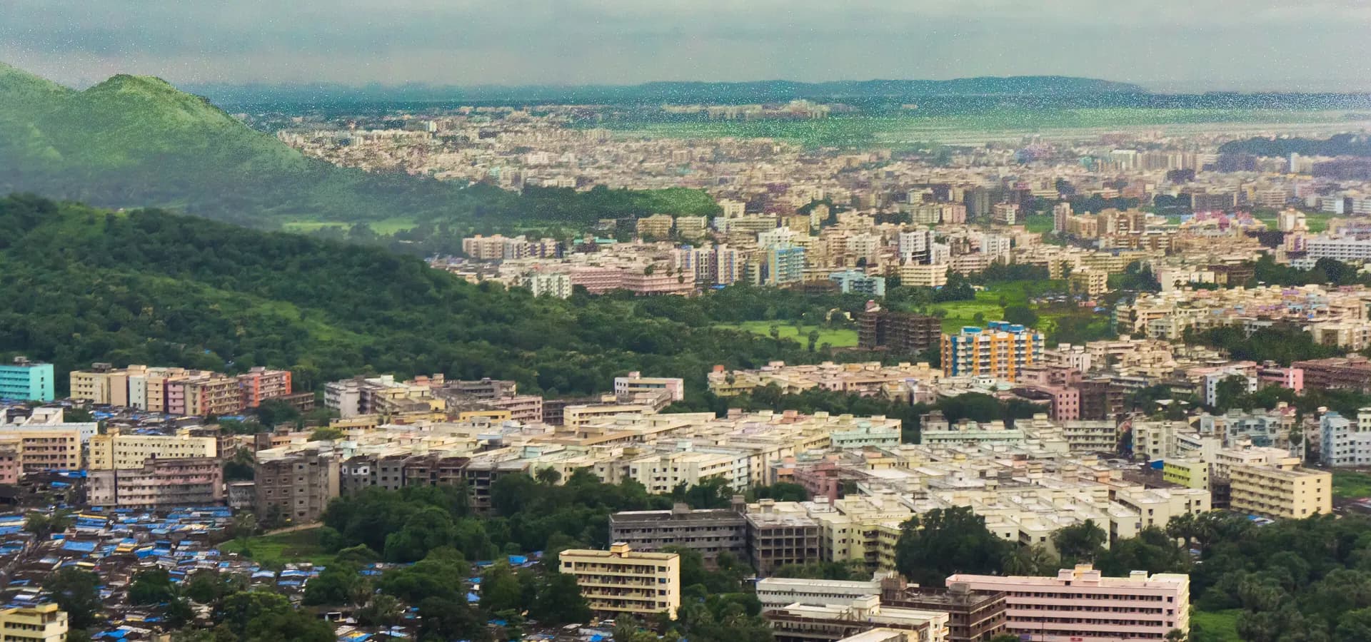 Los edificios de apartamentos de Virar se extienden por la llanura bajo la colina de Jivdani, con laderas verdes y nubes de monzón