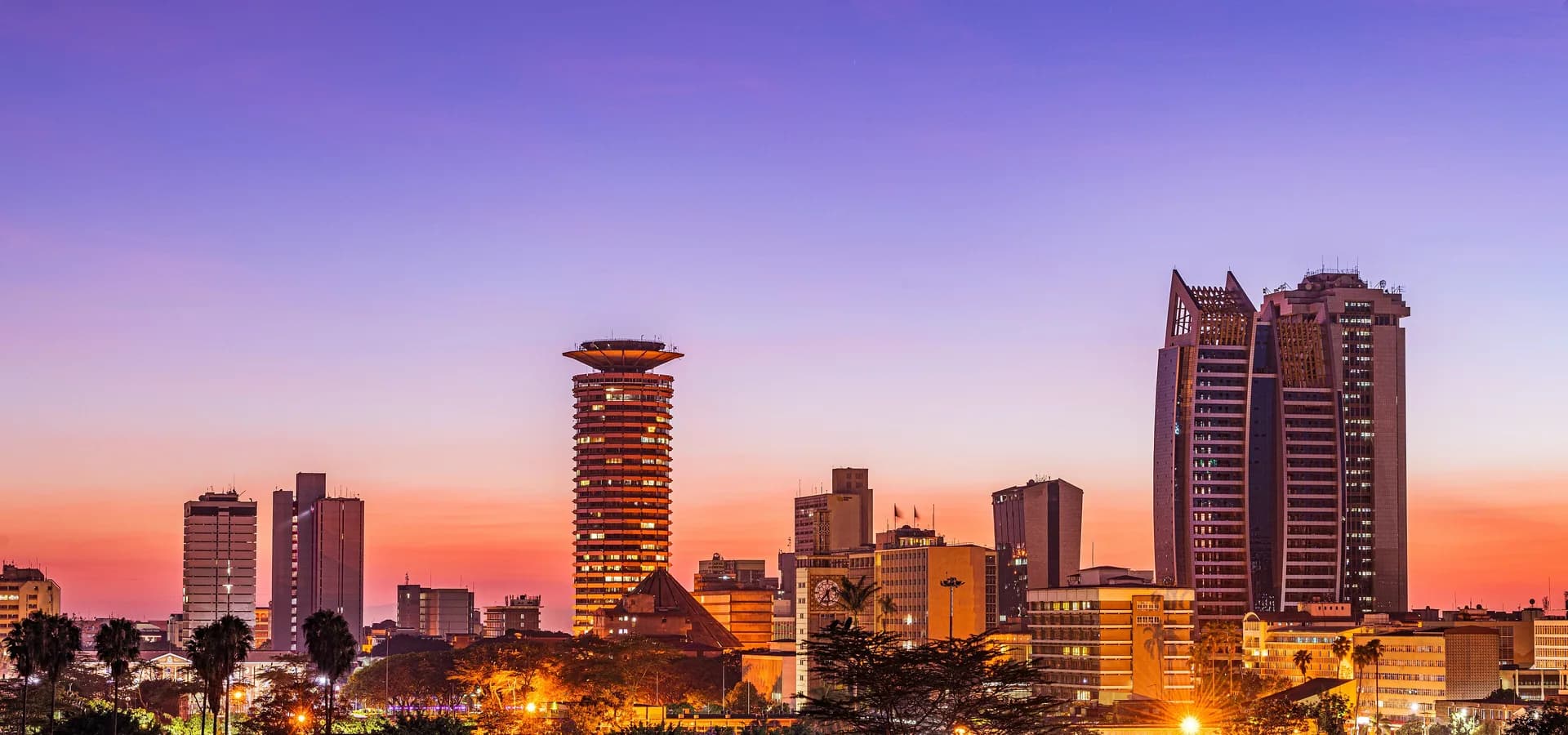 Horizonte de Nairobi al atardecer, con la torre KICC y rascacielos de cristal brillando bajo un cielo violeta y naranja