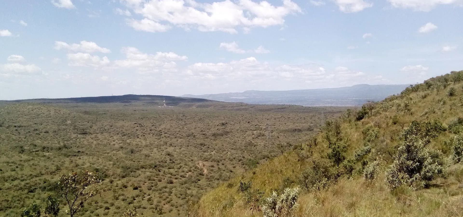 Amplia vista desde el borde del cráter Menengai sobre el verde fondo de la caldera y las colinas lejanas del Valle del Rift
