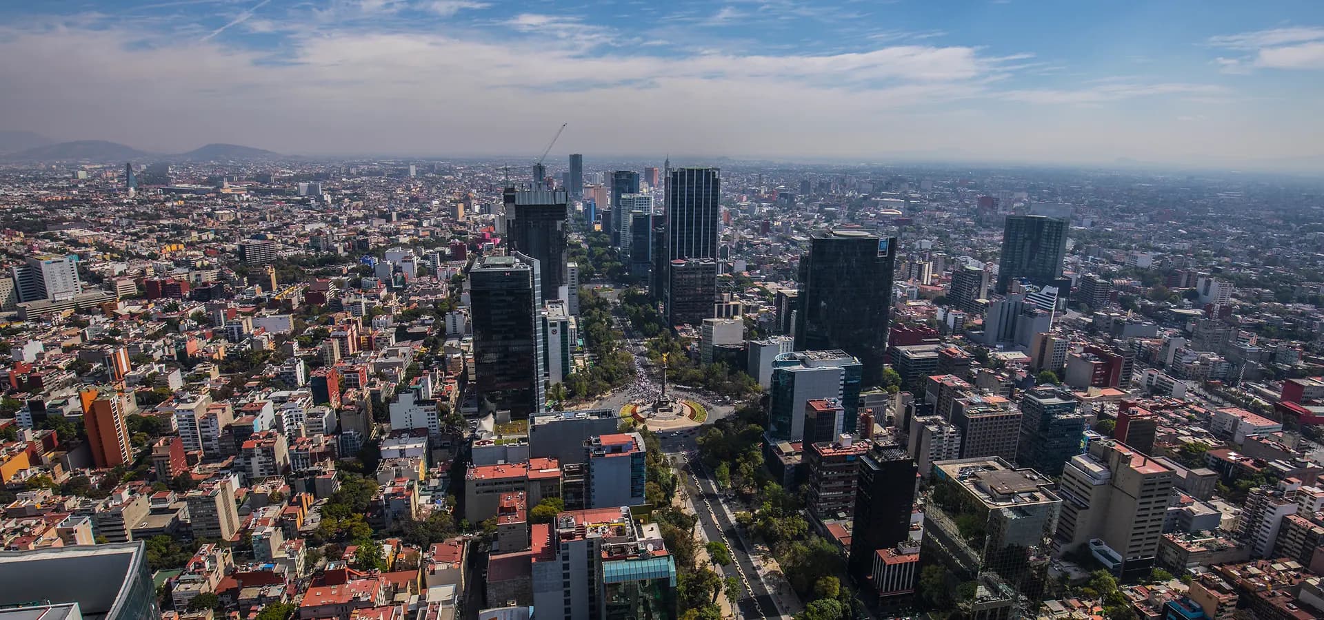 Luftaufnahme von Mexiko-Stadt entlang des Paseo de la Reforma, Glastürme und der Engel der Unabhängigkeit unter weitem blauem Himmel