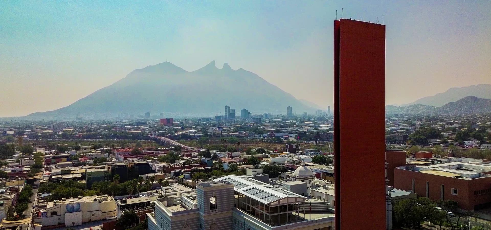 Luftbild des Zentrums von Monterrey mit dem sattelförmigen Cerro de la Silla und dem orangefarbenen Turm Faro del Comercio