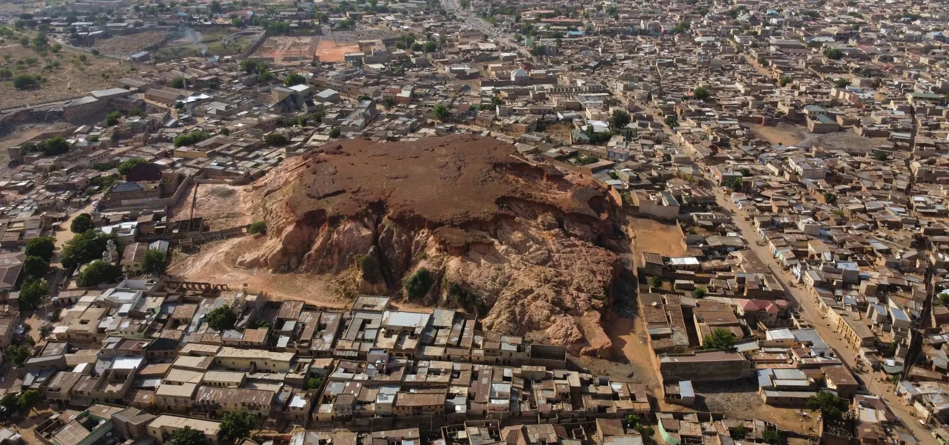 Vista aérea da Colina Dala, um morro rochoso vermelho que surge de um denso tapete de telhados baixos em Kano