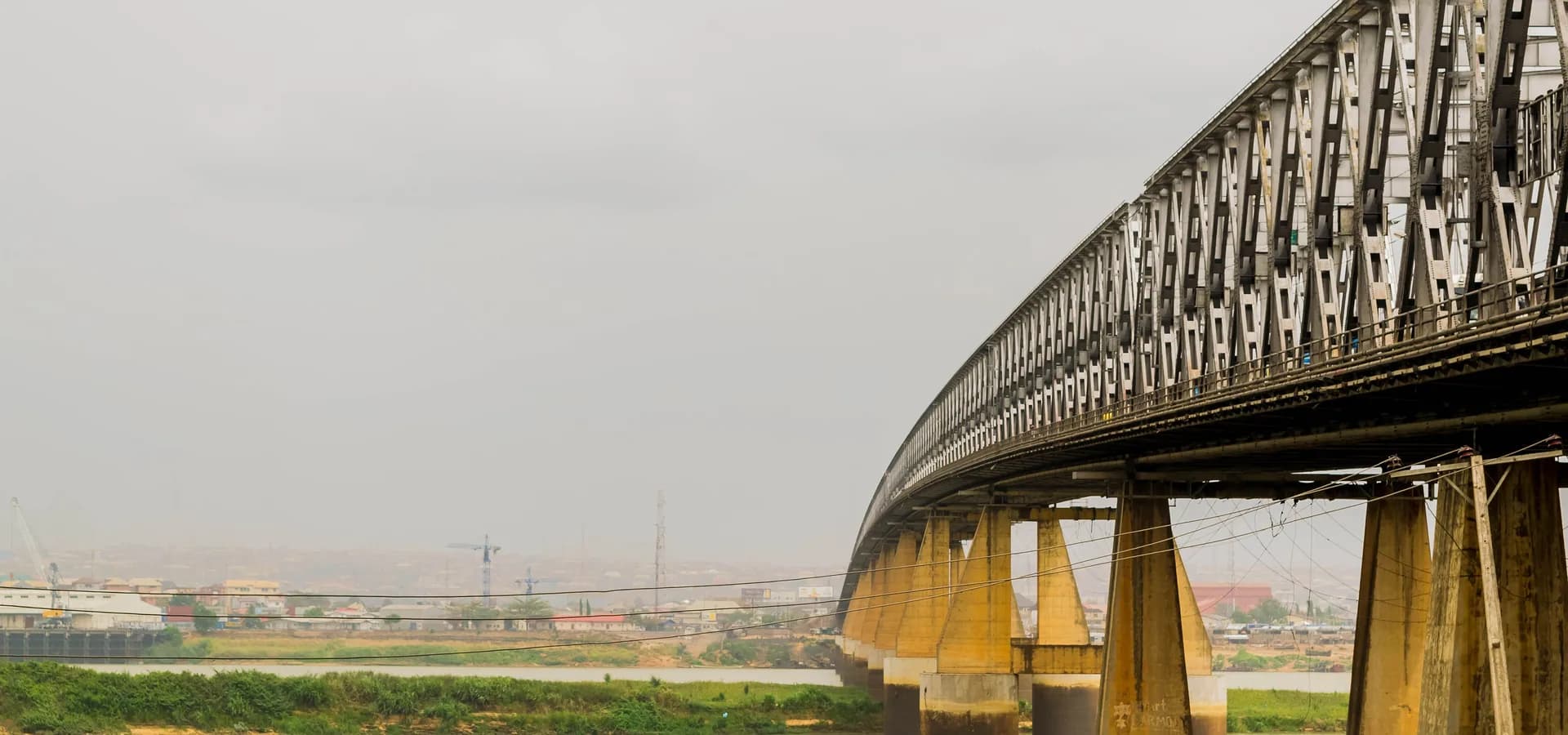 El puente de celosía de acero del río Níger curvándose sobre el ancho río en Onitsha, con la ciudad en la orilla opuesta