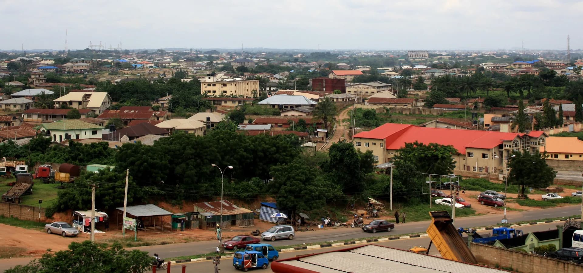 Vista amplia de Osogbo, con techos rojos y grises entre árboles verdes que se extienden hasta el horizonte bajo un cielo pálido