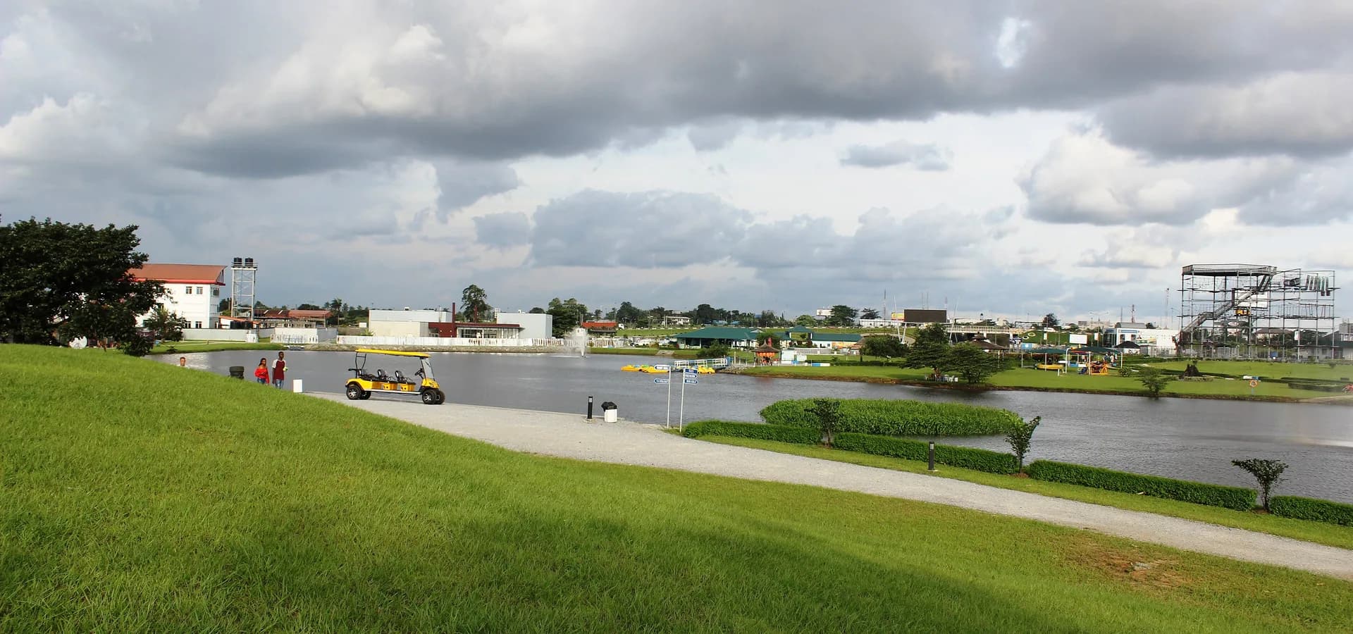 Green lawns sloping to the lake of Port Harcourt Pleasure Park under big rain clouds