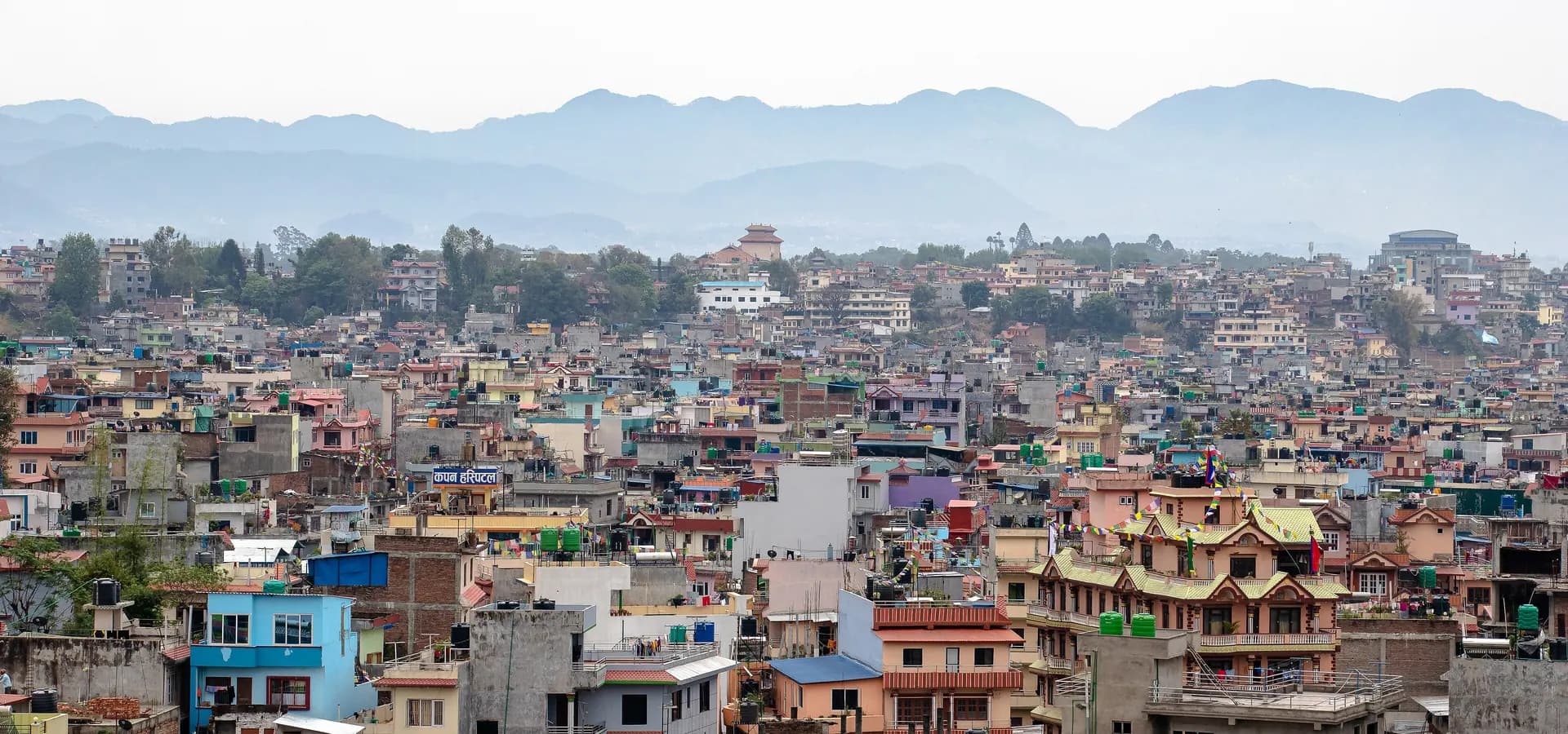 Telhados coloridos de Katmandu se espalhando rumo a colinas azuis em camadas na borda do vale