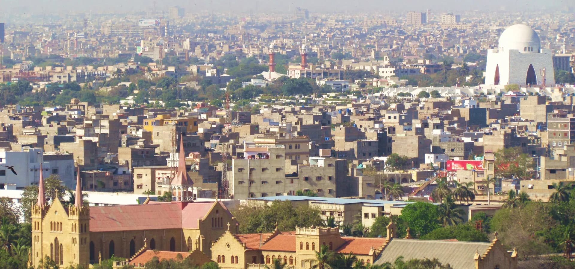 Dächer der Innenstadt von Karatschi bis zum Horizont, darunter die St Patrick's Cathedral und die weiße Kuppel des Mazar-e-Quaid