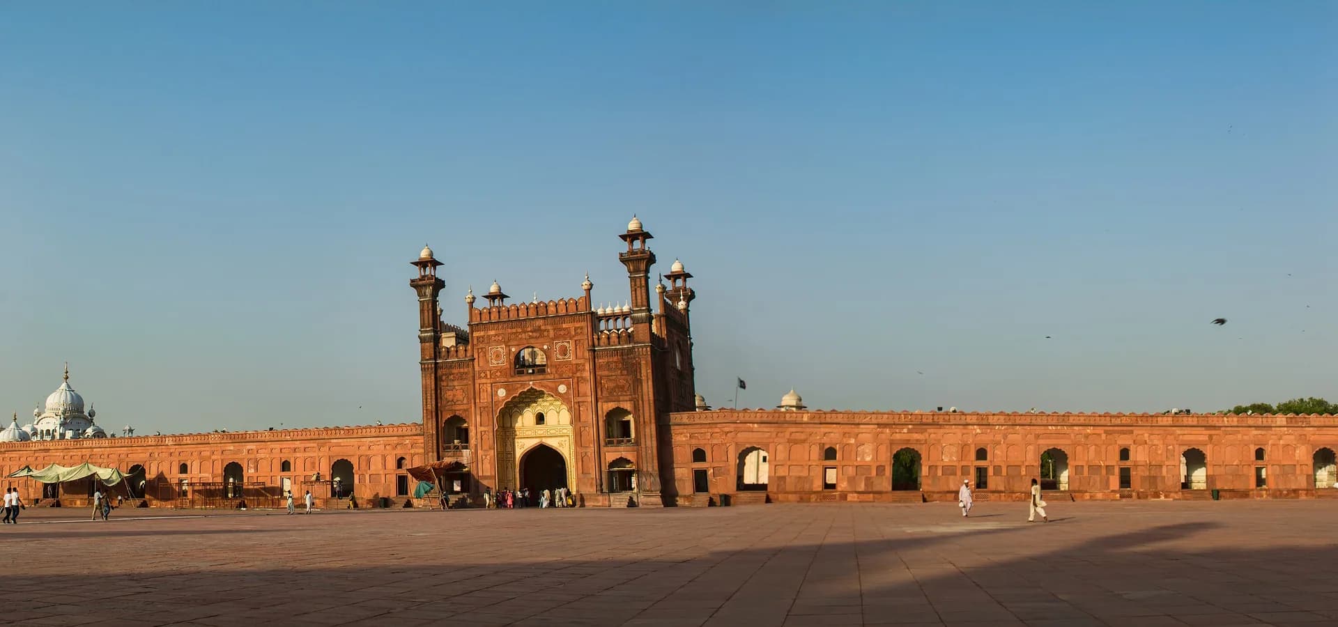Amplio patio de arenisca roja de la Mezquita Badshahi en Lahore, con su gran portal y altos minaretes