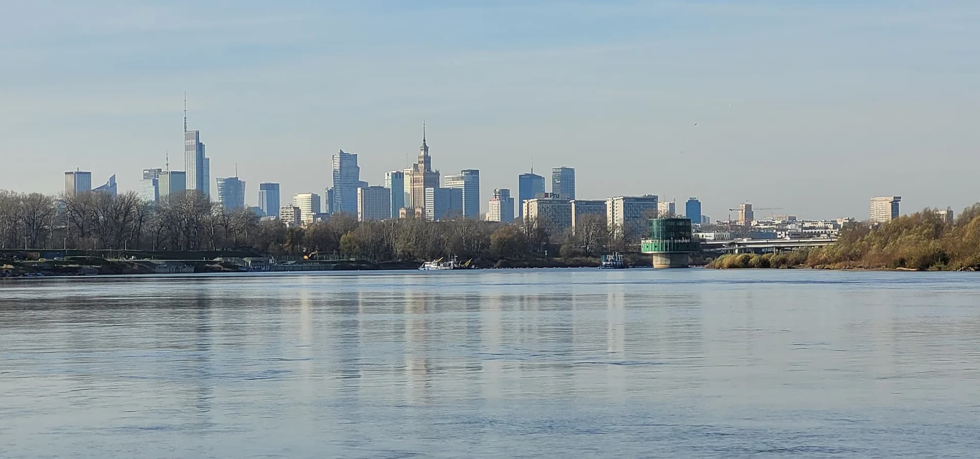 Skyline von Warschau mit Kulturpalast und hohen Türmen hinter der breiten, ruhigen Weichsel
