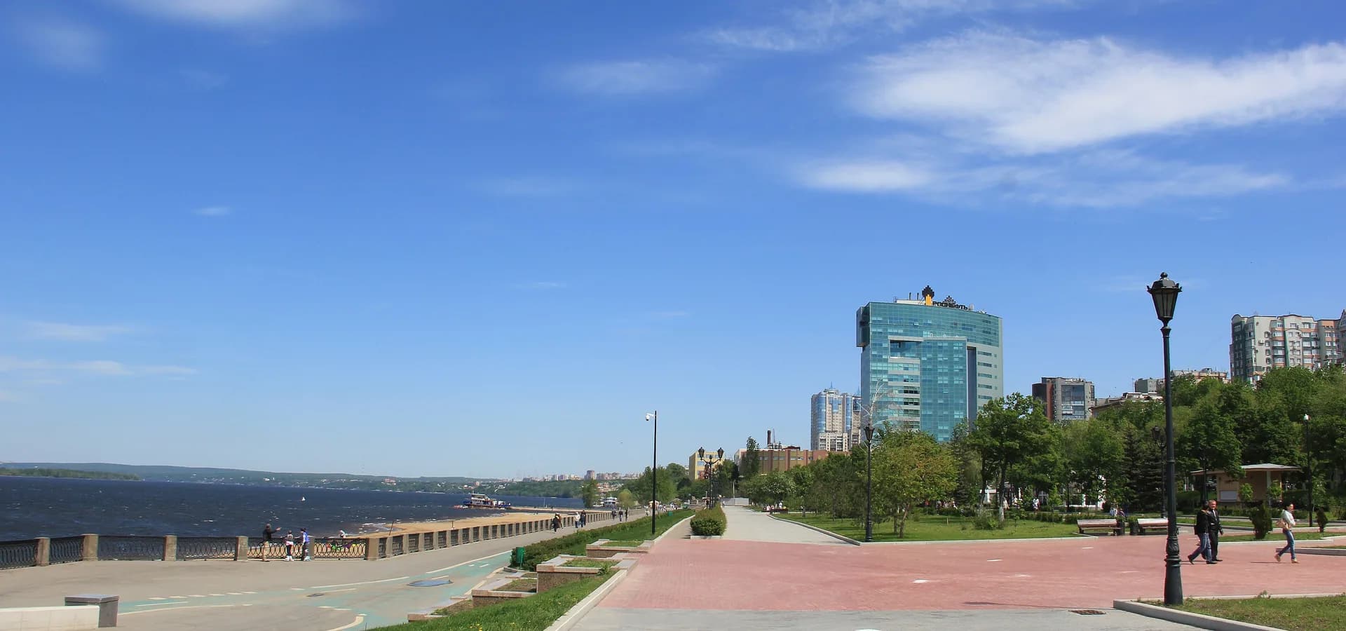Wide Volga embankment promenade in Samara under a blue sky, the river and far green bank on the left