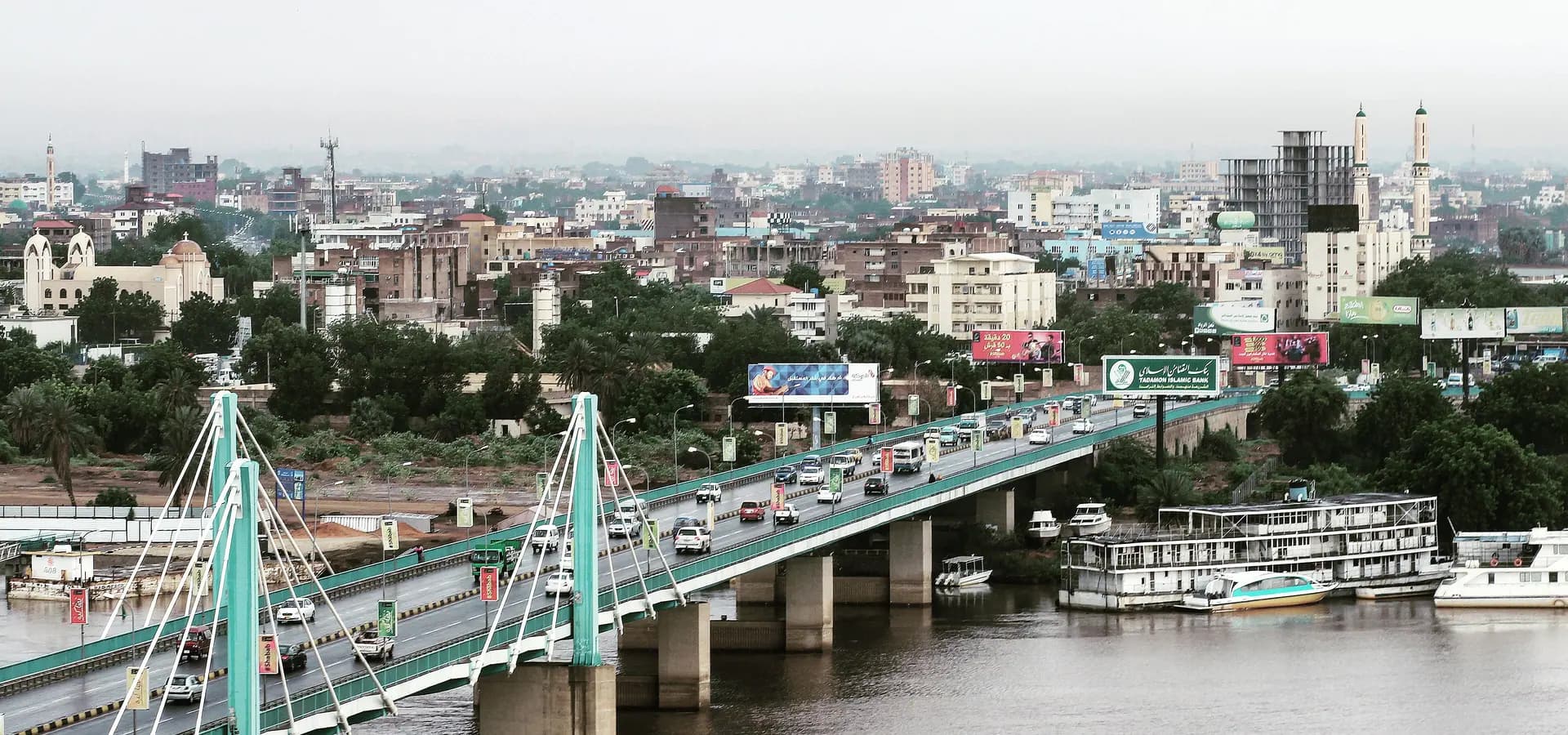 Un puente atirantado con tráfico sobre el Nilo Azul, con los edificios y minaretes de Jartum detrás